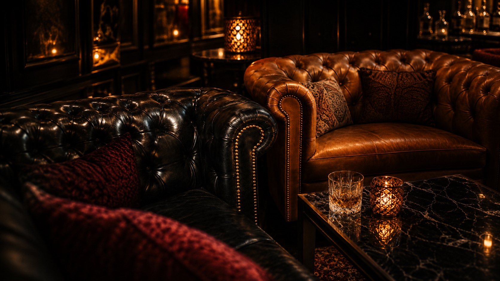 Tufted leather chesterfields with brass studs, whiskey, and candlelight